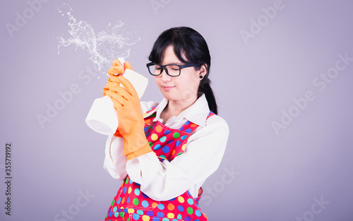 Asian Woman cleaning and polishing the kitchen worktop with a spray detergent, housekeeping and hygiene concept, accessories studio shot isolated on Gray background 