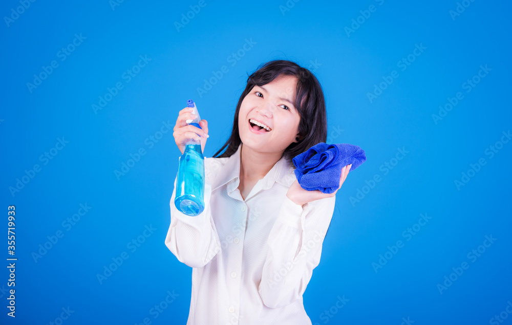Asian Woman cleaning and polishing the kitchen worktop with a spray detergent, housekeeping and hygiene concept, accessories studio shot isolated on blue background Asian Woman cleaning and polishing the kitchen worktop with a spray detergent, housekeeping and hygiene concept, accessories studio shot isolated on blue background