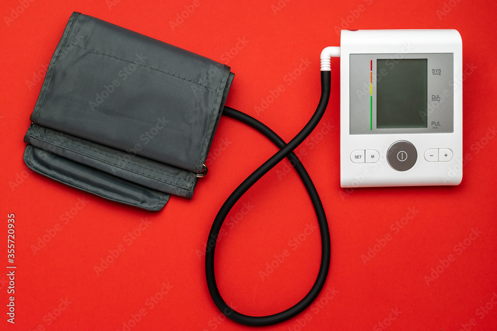 Medical instruments life. Heart hypertension check with sphygmomanometer for doctor, patient. Medical test monitor for blood pressure isolated on red background. Flat lay, top view, copy space. Medical instruments life. Heart hypertension check with sphygmomanometer for doctor, patient. Medical test monitor for blood pressure isolated on red background. Flat lay, top view, copy space.