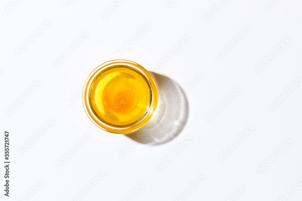Honey in a small glass plate on a white background. Nearby lies a wooden spoon Honey in a small glass plate on a white background. Nearby lies a wooden spoon