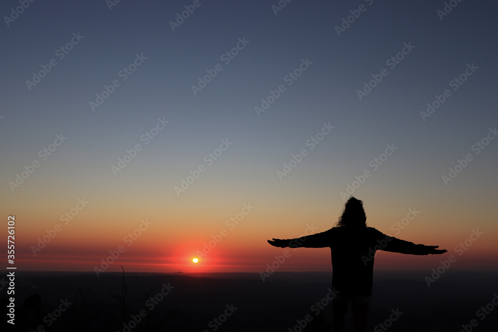 Woman opens arms and rests by the sunset in Portugal. woman .
Silhouette of woman at sunset