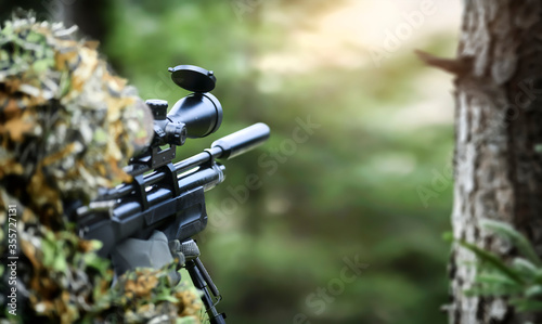 Hunter in camouflage uniform aim with gas air rifle. Soldier ifles with telescopic sight