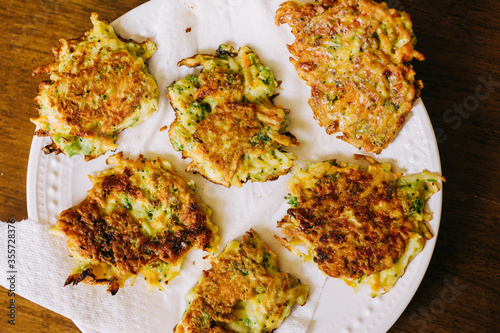 A great toddler meal idea, these vegetable fritters are made with shredded potato, frozen vegetables, egg, and cheese. They are served on a white plate on a wood table. 