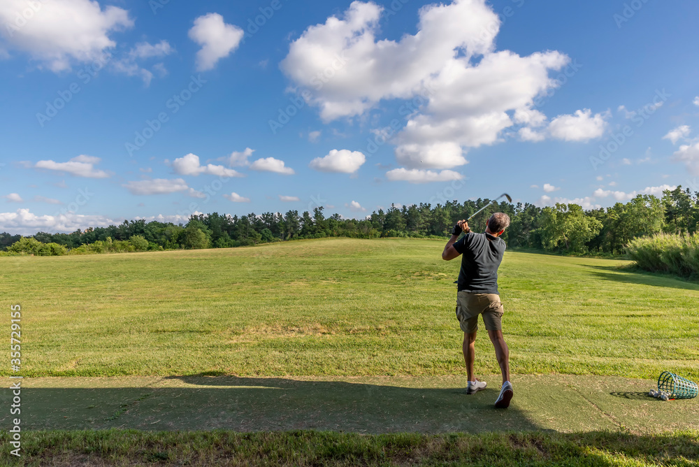 Golf player trains in a driving range completely immersed in the Tuscan countryside near Pisa, Italy Golf player trains in a driving range completely immersed in the Tuscan countryside near Pisa, Italy