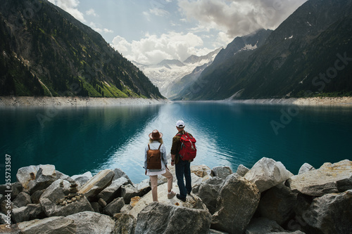 Travelers couple look at the mountain lake. People with a backpack travel. Adventure and travel in the mountains region. Zillertal Alps, Austria. © Alexander