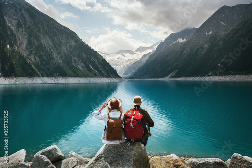 Travelers couple look at the mountain lake. People with a backpack travel. Adventure and travel in the mountains region. Zillertal Alps, Austria.