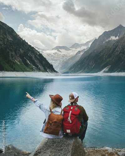 Travelers couple look at the mountain lake. People with a backpack travel. Adventure and travel in the mountains region. Zillertal Alps, Austria.