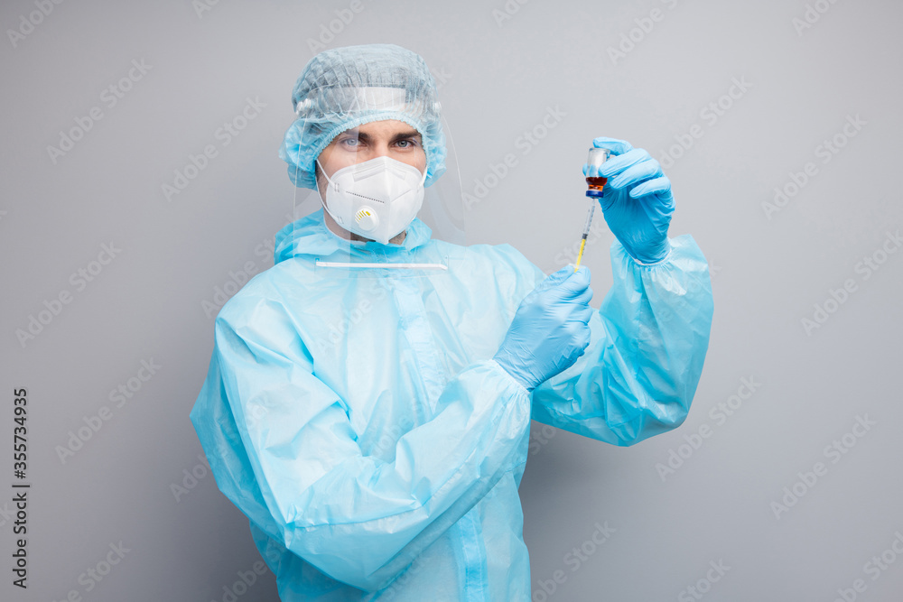 Photo of guy expert doc virologist prepare antibiotic bottle injection sick patient fever wear mask hazmat uniform suit plastic facial protective shield isolated grey color background
