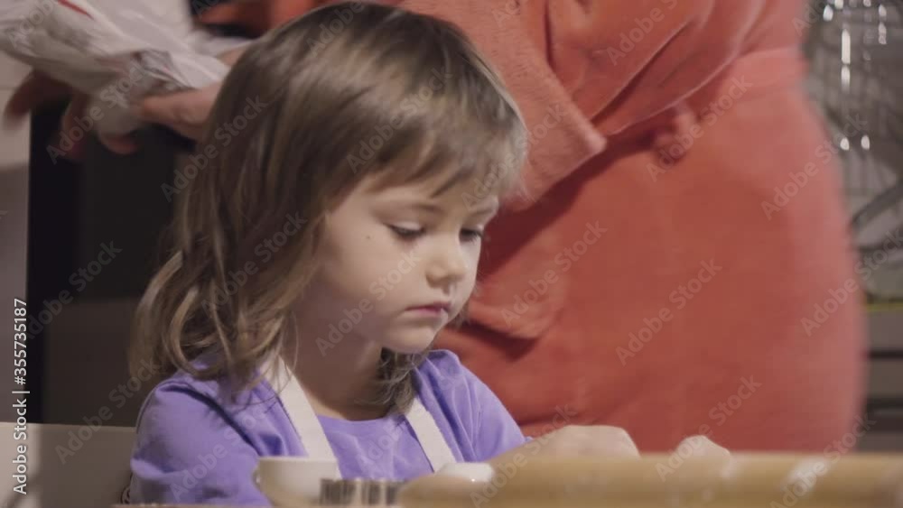 Charming little girl making biscuits at the kitchen table Charming little girl making biscuits at the kitchen table