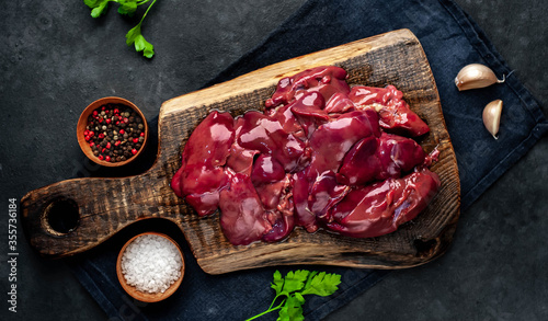  Raw chicken liver on a cutting board on a stone background. View from above. Space for text