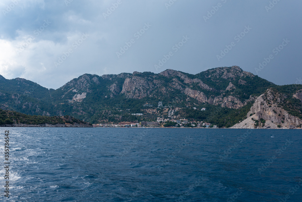 Calm dark blue sea and sky with a mountains and small town in the background