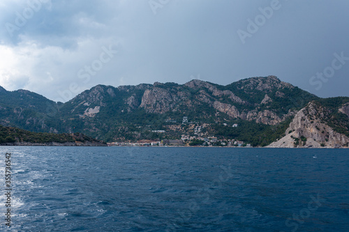 Calm dark blue sea and sky with a mountains and small town in the background