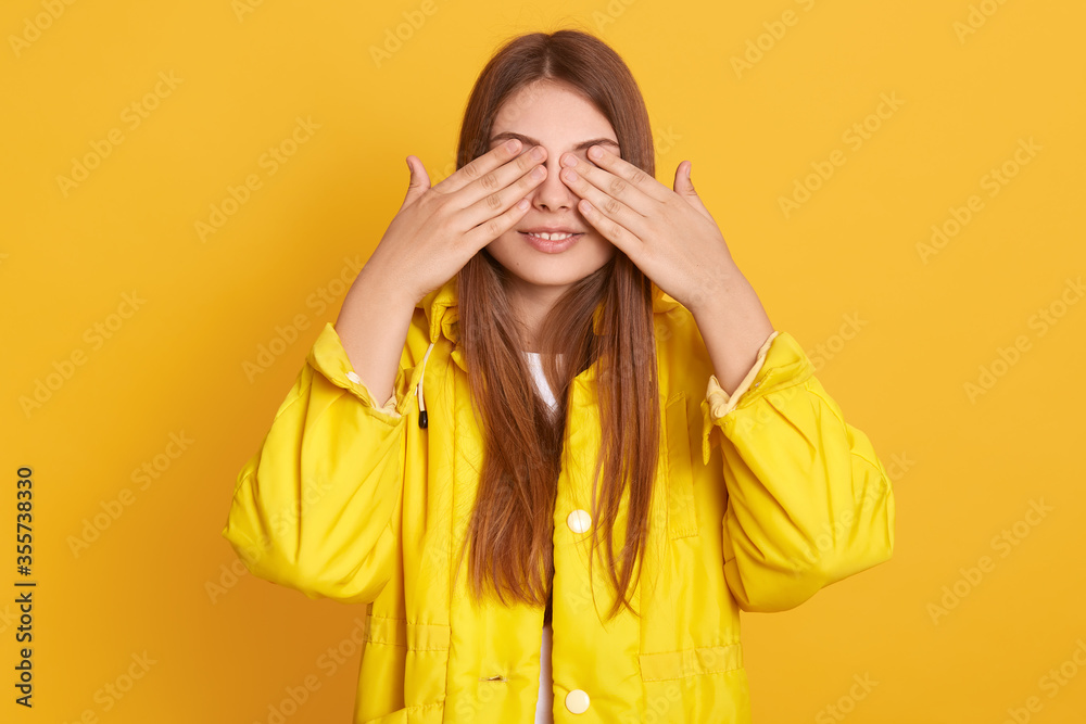 Smiling woman posing indoor and covering he reyes with her palms, lady wearing jacket, hiding from somebody, expressing positive emotions, female having long dark hair. Smiling woman posing indoor and covering he reyes with her palms, lady wearing jacket, hiding from somebody, expressing positive emotions, female having long dark hair.