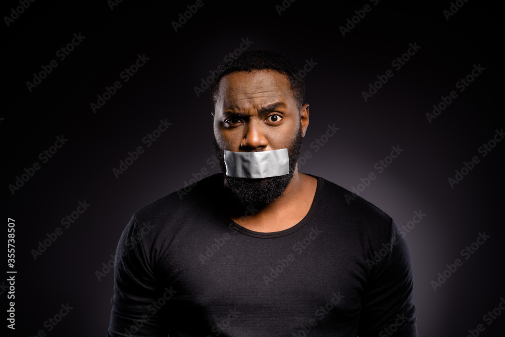 Close up photo of shocked afro american guy close cover lips mouth adhesive tape speechless voiceless african community member racism indifference isolated over black color background Close up photo of shocked afro american guy close cover lips mouth adhesive tape speechless voiceless african community member racism indifference isolated over black color background