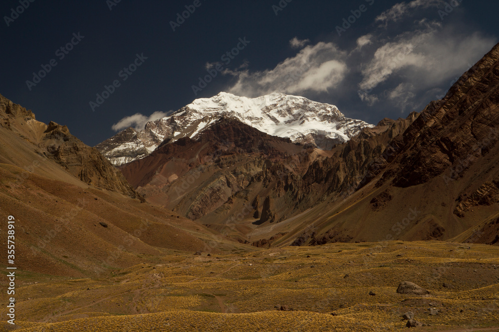 Aconcagua mountain snowy peak and golden valley meadow. Panorama view of Mount Aconcagua in Mendoza, Patagonia Argentina. Aconcagua is one of the world's seven summits