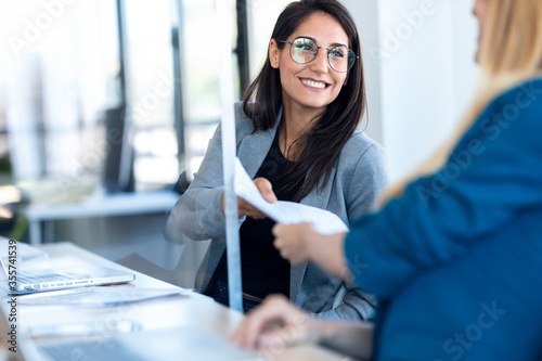Two business women passing documents with keeping a distance in the office.
