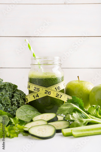 Health concept. Healthy green smoothie and tape measure and ingredients on white - superfoods, detox, diet, health, vegetarian food concept surrounded by ingredients