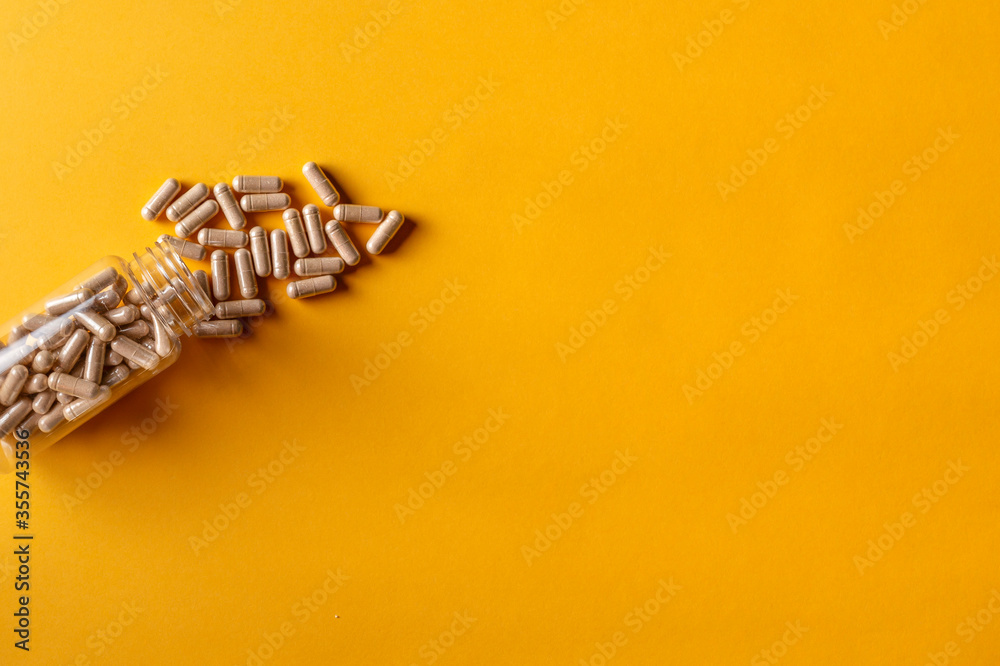open pill bottle on a yellow background and all pills out of the container open pill bottle on a yellow background and all pills out of the container