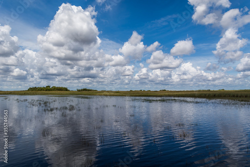 Reflection of clouds in calm water. Wetlands in Florida. Everglades national park. Airboat tourist attraction. Wide shot