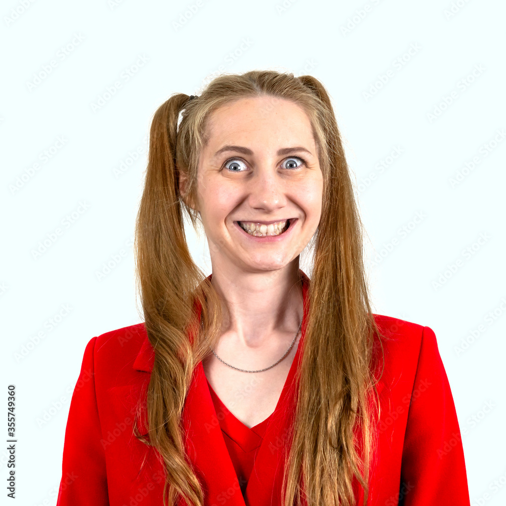 A beautiful student girl with long hair gathered in two ponytails smiled in surprise and looks at the camera, dressed in a red coat. Isolated on a white background. Concept of human emotions. A beautiful student girl with long hair gathered in two ponytails smiled in surprise and looks at the camera, dressed in a red coat. Isolated on a white background. Concept of human emotions.