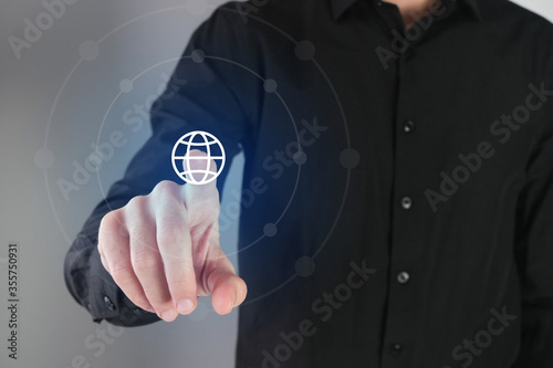 Business man pressing a world icon button on a virtual digital interface. Network concept..