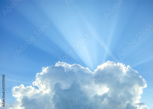 Cumulonimbus cloud with sun rays under bright blue sky at daytime 