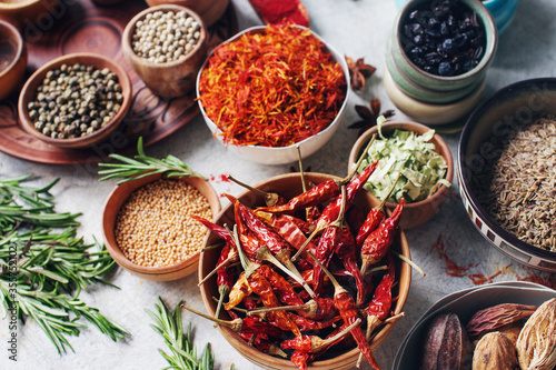 Colorful indian spices and herbs in bowls on light concrete table