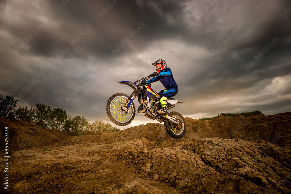 Professional Motorcycle Rider Driving on the mountains and Further Down the Off-Road Track. It's Sunset. Professional Motorcycle Rider Driving on the mountains and Further Down the Off-Road Track. It's Sunset.