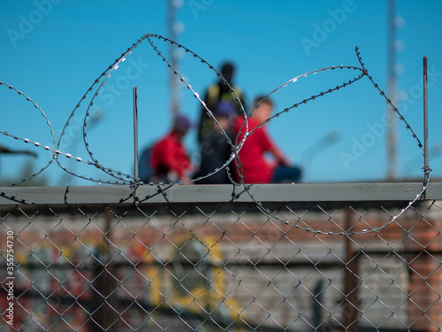 Children siting on garage roof behind the barbed wire