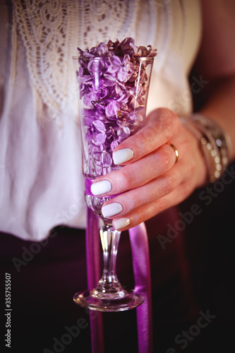 A glass with lilac flowers in the hands of a girl. High quality photography