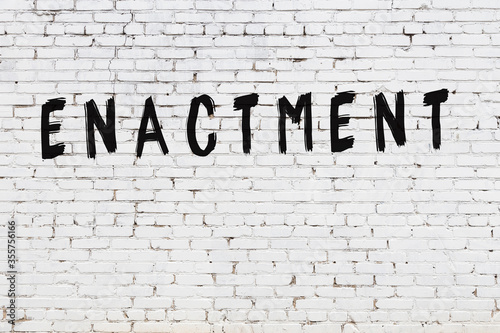 Word enactment painted on white brick wall