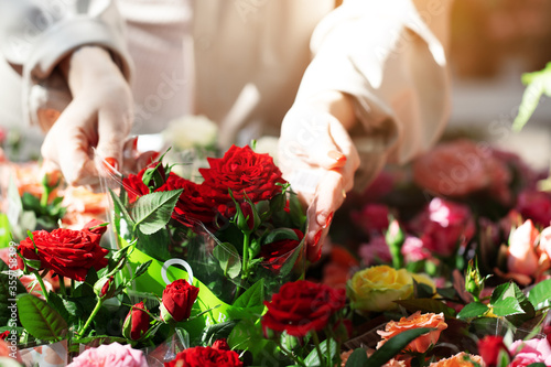 Woman hands customer shopping in a greenhouse  choosing a purchase of red roses bouquet. In a flower shop  sales and retail  small business  florist work.  Gardening hobby