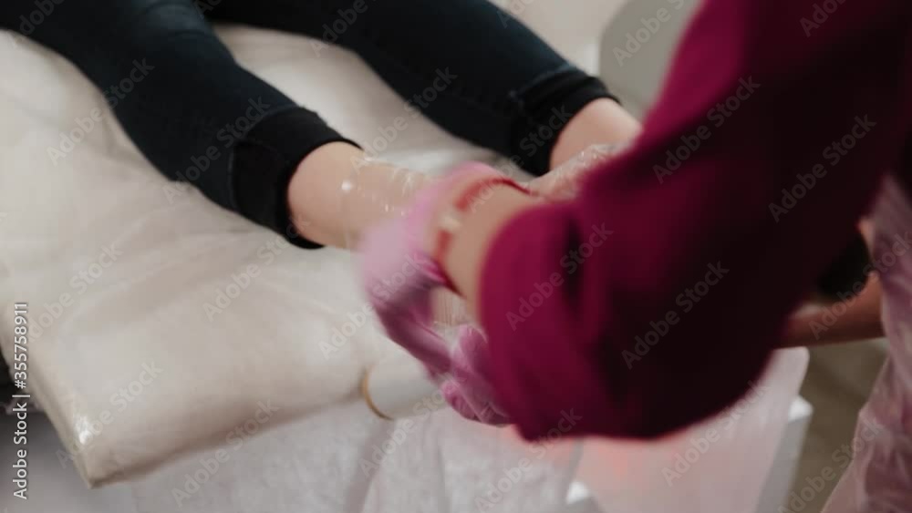Pedicure master wraps a girl s legs with foil. Pedicure master wraps a girl s legs with foil.