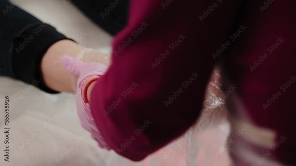 Pedicure master wraps a girl s legs with foil. Pedicure master wraps a girl s legs with foil.