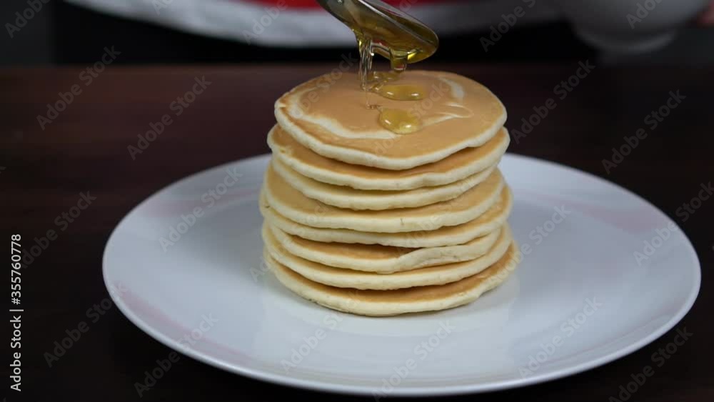 Delicious pancakes. Sweet maple syrup pours onto a stack of pancakes in super slow motion. American Pancakes. Delicious pancakes. Sweet maple syrup pours onto a stack of pancakes in super slow motion. American Pancakes.