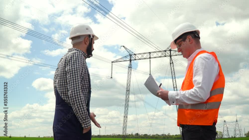 Two engineers working near transmission lines. Manager accepts a report on the operation of power lines. Energy efficiency conception