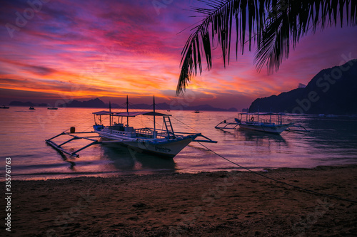 Traditional boats on the background of a bright sunset and a series of tropical Islands