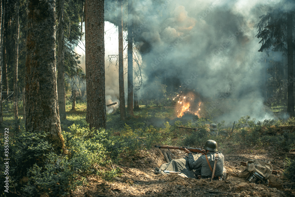 Reconstruction of the battle in the forest, a soldier shoots from a trench, an explosion in the background Reconstruction of the battle in the forest, a soldier shoots from a trench, an explosion in the background