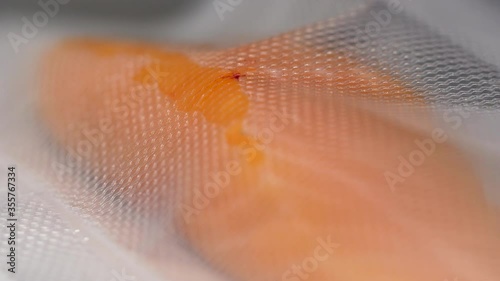 Close-up of raw salmon fish fillet getting vacuum packed into airtight pouch for long term storage. 