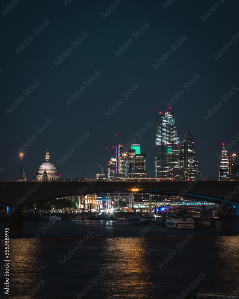 Bright nigh skyline of London city with the financial district skyscrapers, St Paul's Cathedral and the Thames river 