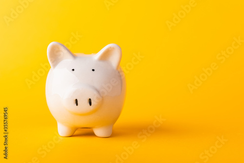 Front small white fat piggy bank, studio shot isolated on yellow background and copy space for use, Finance, deposit saving money concept