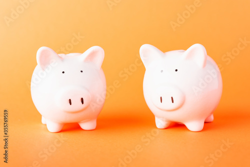 International Friendship Day  Front two small white fat piggy bank  studio shot isolated on orange background and copy space for use  Finance  deposit saving money concept