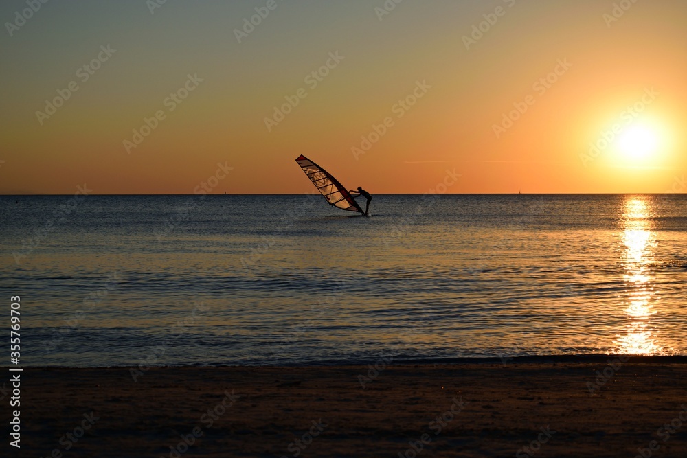 seascape at sunset time in the tourist resort of Vada in the municipality of Rosignano Marittimo in Livorno, Tuscany, Italy with a wind surfer who practices sports
