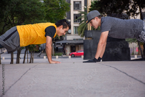 Two young men do exercise together in a park © ERNESTO