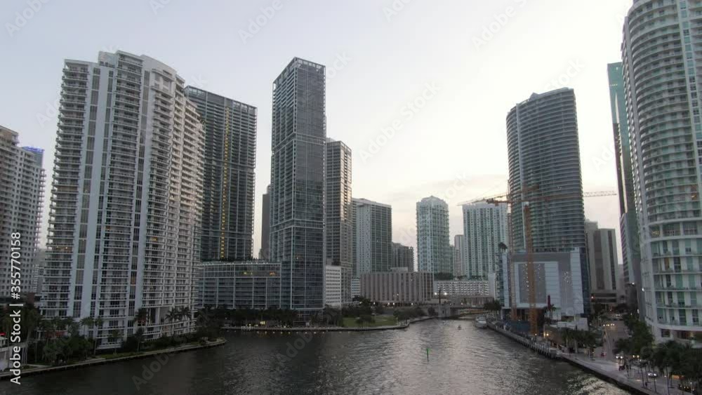 Aerial shot of canal against skyscrapers in city during sunset, drone flying backward from buildings against sky - Miami, Florida Aerial shot of canal against skyscrapers in city during sunset, drone flying backward from buildings against sky - Miami, Florida