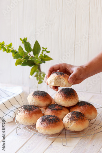 Fresh homemade burger buns with poppyseed, concept of burger and homemade food. Mini challah. Homemade bread. Bread in man's hand photo