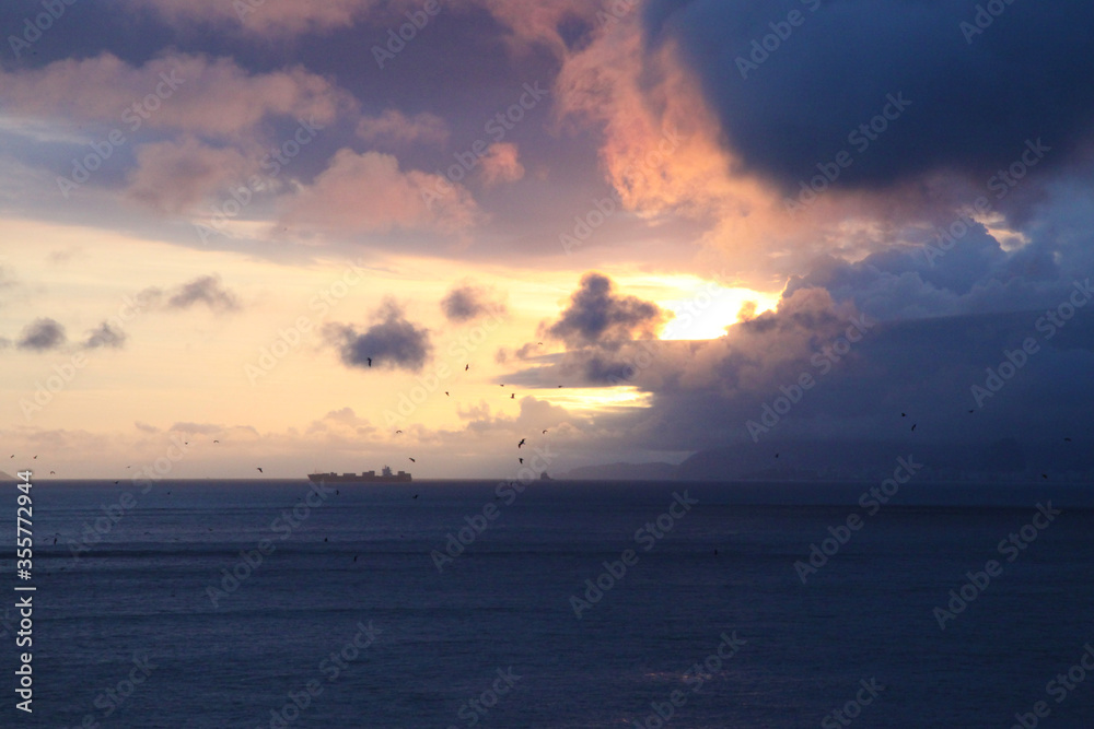 Pôr-do-sol no mar com navio e gaivotas