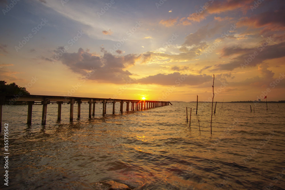 Beautiful sunset scenery at seascape with long jetty background.