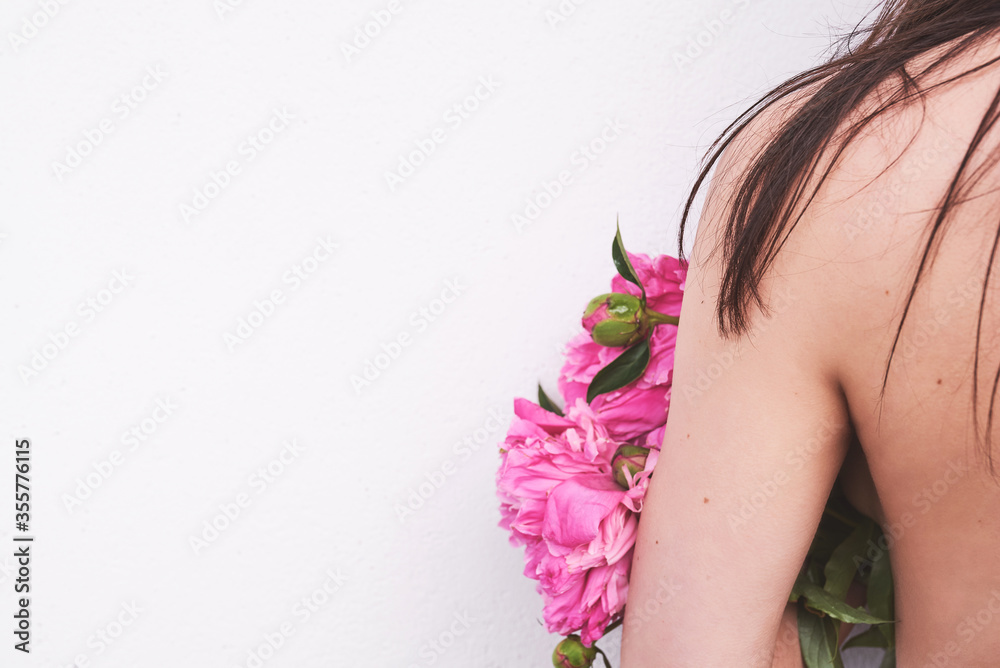 Girl holds pink peonys. Close-up of her back. Brunette. Space for text on white background
