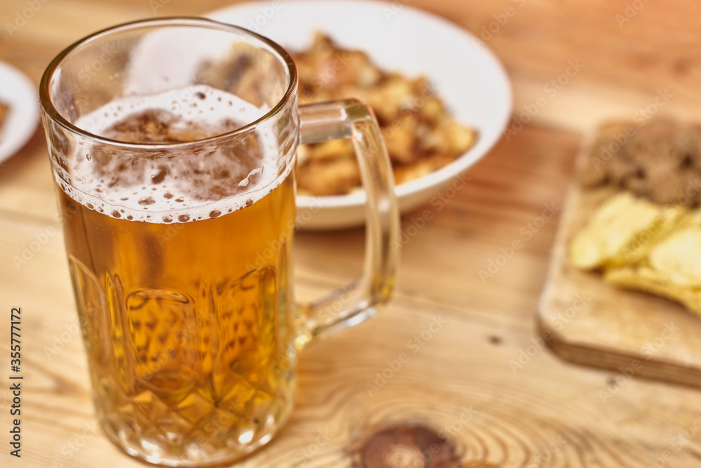 A glass of beer and different snacks on the table. Celebrating international beer day or Octoberfest. Drinking beer after a hard working day or week